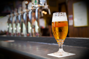 Glass of light beer on a dark pub